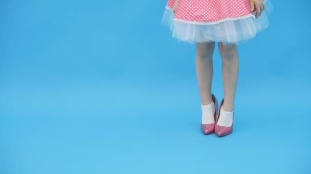 Klein meisje glimlachen voor een foto in roze jurk en op hoge hakken in 4k slowmotion video. — Stockvideo
