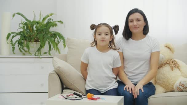 4k вялое видео матери и дочери на белом диване, позирующих для видео. — стоковое видео