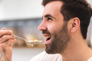 Beyaz arka planda izole edilmiş diyetle mısır gevreği yiyen genç adam..