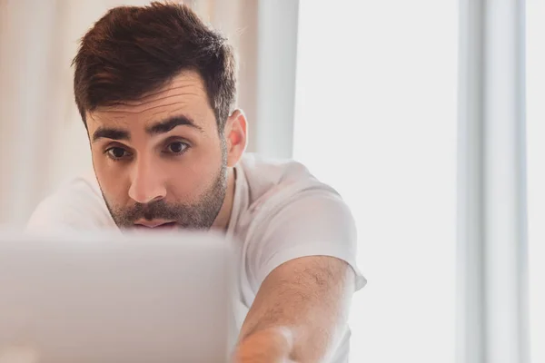 Foto av allvarlig skäggig man som arbetar på laptop medan du spenderar tid hemma. — Stockfoto