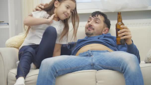 4K videoda küçük kızı ve babası beyaz kanepede birlikte içki içiyorlardı.. — Stok video