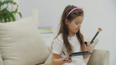 Küçük kızın 4k yavaş çekim videosu göz makyajı ve yüz resmi yapıyor..