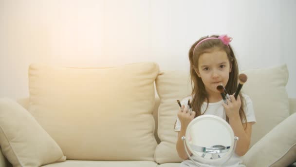 4k slow motion vídeo de chils sorridentes menina segurando escovas cosméticas na sala de estar. — Vídeo de Stock