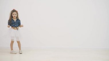 4k yavaş çekim videosu, beyaz arka planda benekli küçük bir kız dans ediyor..