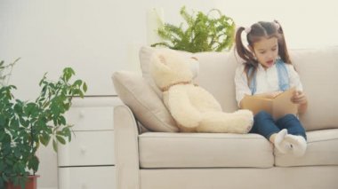 Küçük uykucu kız 4K yavaş çekim videosunda kitap okuyor..