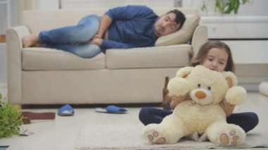 Yalnız çocuk yerde oyuncak ayıyla oynuyor. 4K yavaş çekim videosunda..