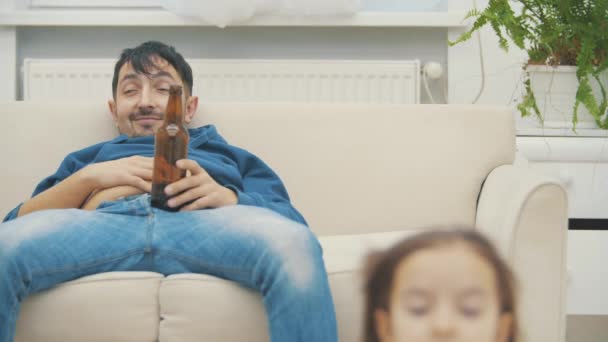 4k slowmotion видео, где отец сидит на диване и не обращает внимания на свою маленькую дочь. — стоковое видео