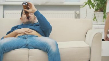 4k video 'da küçük kız ve babası birlikte içki içip beyaz kanepede gülüyorlar..