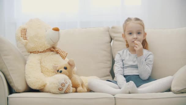 4k close up video de la pequeña hija rubia comiendo plátano y escuchando a alguien. — Vídeos de Stock