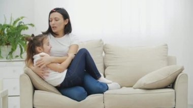 4k video 'da anne ve kızının oturma odasındaki beyaz koltukta hoş sohbetleri var..