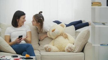 4k video 'da bekar anne kanepede otururken enerjik çocuk kız oynuyor..