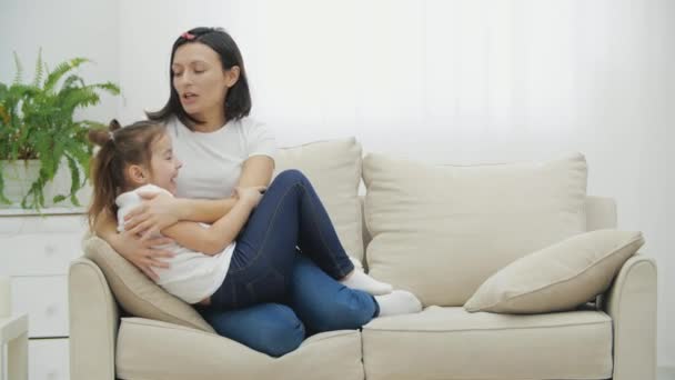 4k video of daughter and mother having pleasant talk on white sofa in the living room. — Stock Video