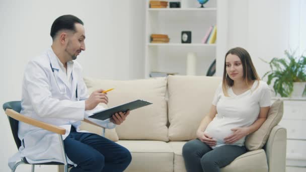 4k video de un médico y una mujer embarazada en consulta. — Vídeo de stock