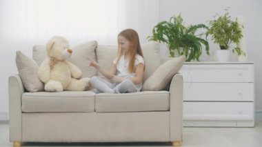 4K yavaş çekimde, oyuncak ayının yanında beyaz elbiseli, üzgün, sarışın bir kızın videosu..