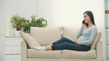 4k yavaş çekimde, koltukta oturan hamile kadının telefonda konuştuğu video..