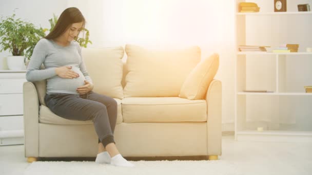 Vidéo ralenti 4k de la femme enceinte touchant son estomac et regardant la caméra. — Video