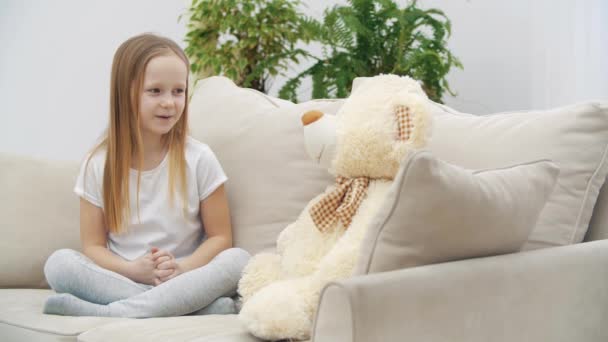 4kビデオの小さな女の子で白い服と話をテディベア. — ストック動画