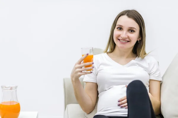 Foto von schwangerer Frau mit einem Glas Orangensaft und Blick in die Kamera. — Stockfoto