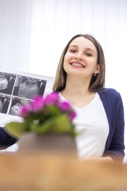 Ön planda gülümseyen kadın ve bulanık mor çiçeklerin fotoğrafı.