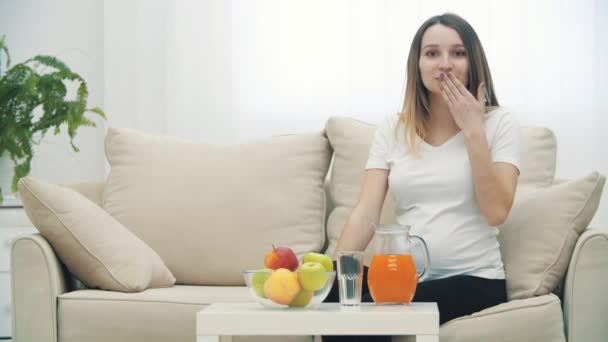 4kビデオの妊娠中の女性座っていますのソファに果物とジュース. — ストック動画