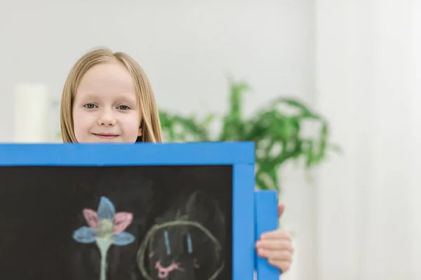 Фото милой маленькой девочки, показывающей свое творение на белой доске. — стоковое фото