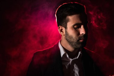 Siyah ve pembe arka planda duman içindeki bir adamın fotoğrafı..