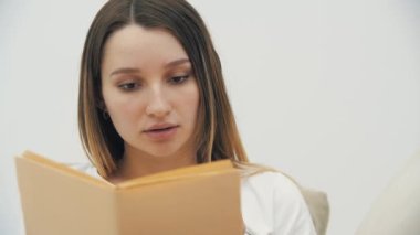 4K yakın çekim videosunda bir kadın kitap okuyor ve elma yiyor..