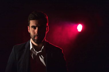 Ayakta duran adamın fotoğrafı ve arka planda pembe ışık..