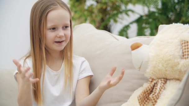 4k vídeo de menina em roupas brancas falando com ursinho de pelúcia. — Vídeo de Stock