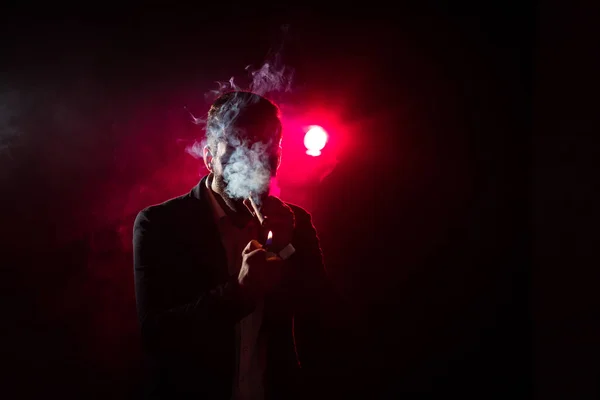 검은 배경 과 핑크 빛에 담배 라이터가 있는 남자의 사진. — 스톡 사진