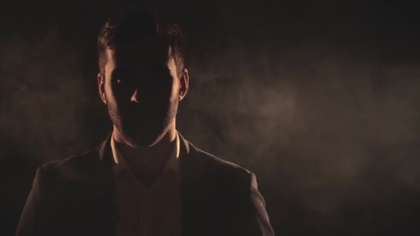 4k крупным планом видео с мужским лицом в тени и дыму. — стоковое видео
