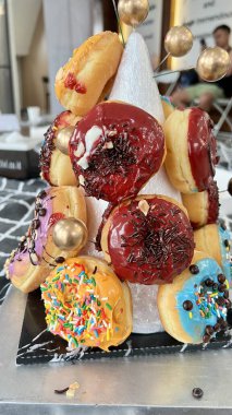 Çeşitli renklerde ve serpiştirilmiş altın broşlu çeşitli çörekler kulesi