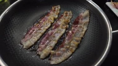 Çubuksuz bal peteği desenli tavada yağla cızırdayan çoklu pastırma şeritlerinin yukarıdan görünüşü, kahvaltı veya sağlıksız yemek kavramları için idealdir.