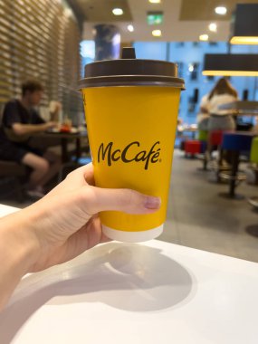 Poznan, Polonya - 11 Eylül 2025: McCafe 'nin sarı kahve bardağını tutan ve popüler, kullanışlı bir fast-food içecek seçeneğini ön plana çıkaran bir el görüntüsü
