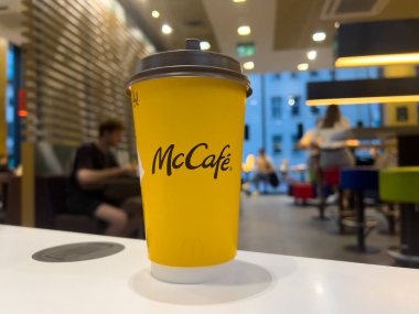 Poznan, Polonya - 11 Eylül 2025: McCafe, beyaz tezgahın üzerinde koyu kapaklı, erişilebilir, popüler McDonald 's kafe içeceklerini yansıtan sarı bardakla damgalandı