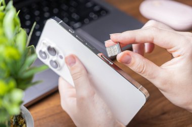 Şebeke etkinleştirmesi, hücresel servis ve dijital yaşam için gerekli adımları vurgulayan, şık ve modern bir cep telefonuna bir mikroçip SIM kartı yerleştiren bir elin yakın plan görüntüsü