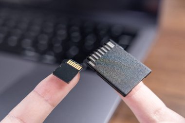 Mikro SD kart ve standart SD kartı gösteren parmakların yakın plan görüntüsü, çeşitli elektronik veri depolama ihtiyaçları için kompakt tasarımlarını vurguluyor