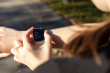 Poznan, Polonya - 24 Eylül 2025: Bir kişinin eli Apple Saati ile etkileşime girer, dışarıda kişisel sağlık denetimi için gerçek zamanlı egzersiz ilerlemesi sergiler