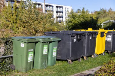 Poznan, Polonya - 24 Eylül 2025: Çevre koruma ve sürdürülebilirliğe olan bağlılığını gösteren sıralı geri dönüşüm için yeşil, siyah, sarı açık hava kutuları