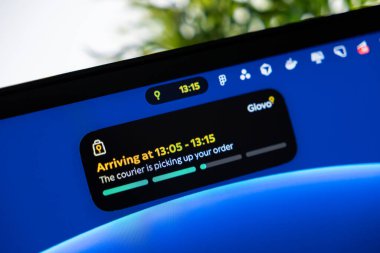 Poznan, Polonya - 1 Ekim 2025: Bir dizüstü bilgisayardaki Glovo uygulamasına yakın çekim, kurye ve tahmini varış süreçleri ile aktif bir gıda siparişi tasvir ediliyor