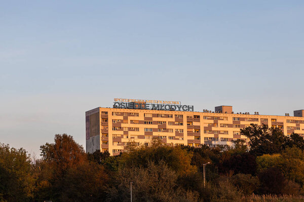 Познань, Польша - 1 октября 2025 года: Сполдзельня Мешканиева Оседле Млодыч вывеска на многоэтажном жилом здании на закате, выделяя городское общежитие