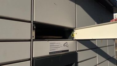 Poznan, Polonya - 10 Ekim 2025: Otomatik dolaba kahverengi bir paket yerleştiren bir insan elinin yakın çekimi, modern, güvenli ve uygun kentsel paket teslimatını vurguluyor