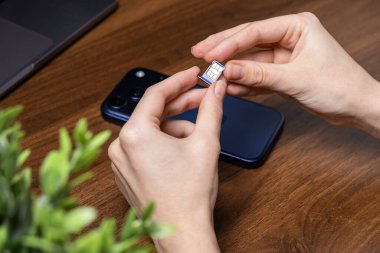 Eller, mobil veriler, küresel telekomünikasyon ve bağlantı hizmetleri için hayati önem taşıyan, modern bir akıllı telefona kurulum tepsisiyle bir SIM kartı hazırlıyor