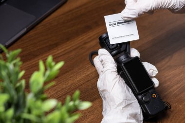 Poznan, Polonya - 16 Ekim 2025: Eldivenli el DJI Osmo Pocket 3, dikkatlice koruyucu ekran etiketini soymak, titiz bir teknik kurulum, bakım ve ürün bakımını vurgulamak