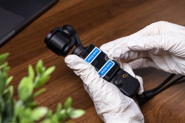 Poznan, Polonya - 16 Ekim 2025: DJI Osmo Pocket el kamerası ahşap bir masada beyaz koruyucu eldivenlerle dikkatlice hazırlanarak içerik oluşturmada hassasiyeti sembolize ediyor