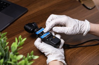 Poznan, Polonya - 16 Ekim 2025: Eldivenli eller, DJI Osmo cep kamerasına şeffaf bir ekran koruyucusu yerleştiriyor, gerekli videografi için optimal görüntü netliği sağlıyor