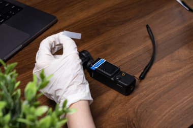 Poznan, Polonya - 16 Ekim 2025: Eldivenli bir el, bir DJI Osmo cep kamerasına uzun ömürlü ve özenli bir cihaz sağlayan açık ekran koruyucusu uygular