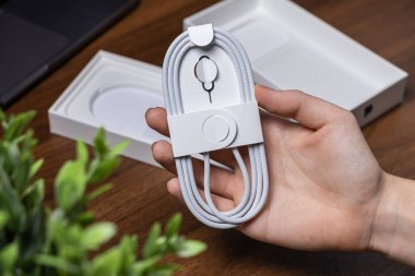 Poznan, Polonya - 16 Ekim 2025: Yeni sarmalanmış beyaz örgülü USB kablo ve SIM fırlatma aracı, mobil aygıtlar için kritik dijital aksesuarlar