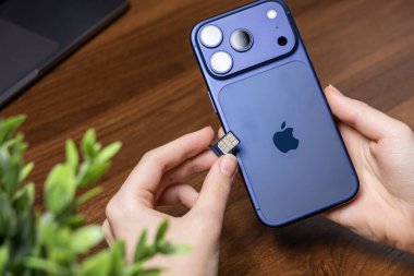 Poznan, Polonya - 16 Ekim 2025: Kullanıcının elleri titizlikle mor iPhone 17 Pro 'ya bir nano SIM kart yerleştirerek önemli cep telefonu verileri ve ses becerileri oluşturdu