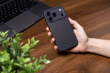 Poznan, Polonya - 16 Ekim 2025: Yerli Birliği 'nin, modern dijital deneyim için sürdürülebilir mobil cihaz koruması sunan iPhone 17 Pro için elde tutulan siyah desenli çanta